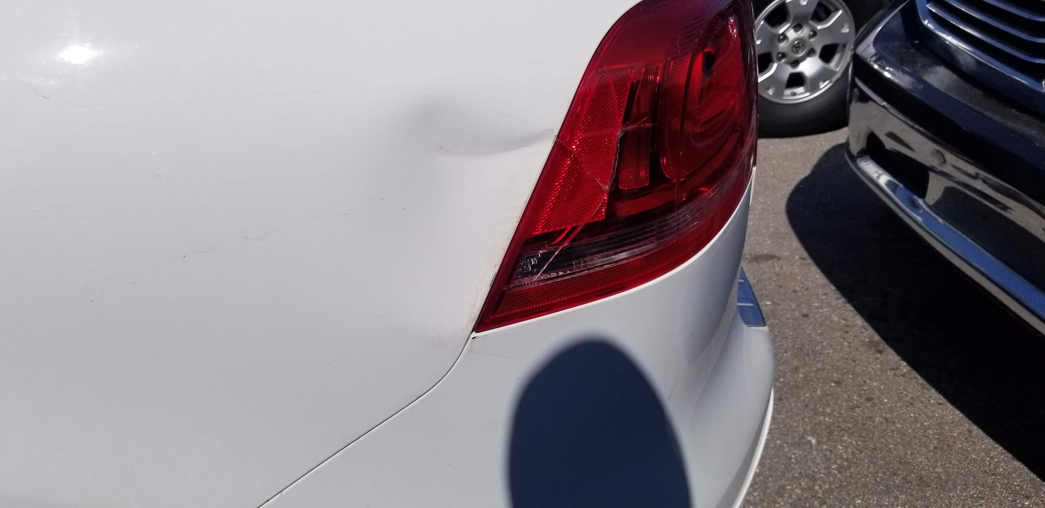 Close-up of paint and body damage near a taillight