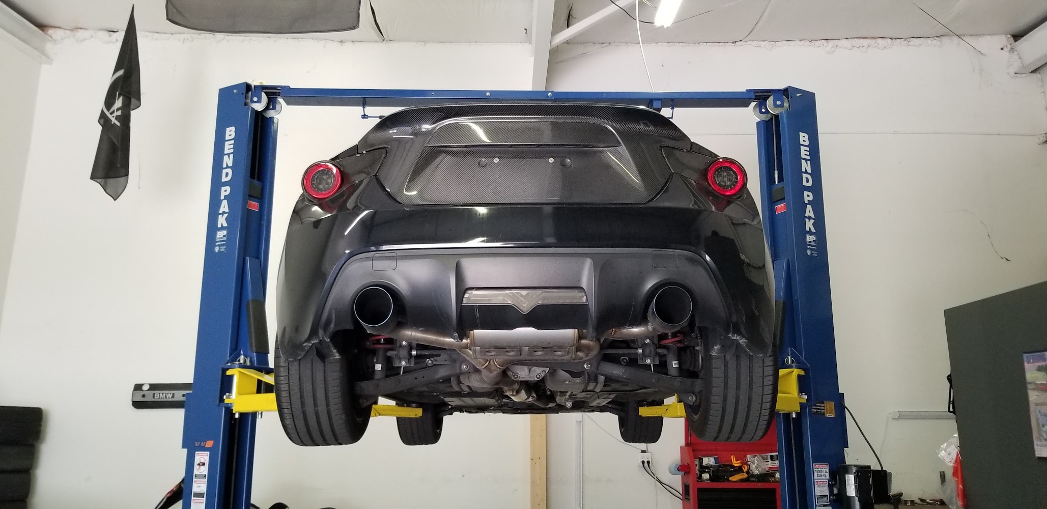 Black sports car raised on a two-post lift